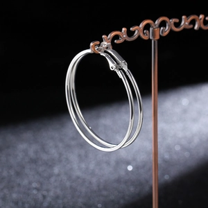 Polished silver large hoop earrings hanging on a vintage metal display stand