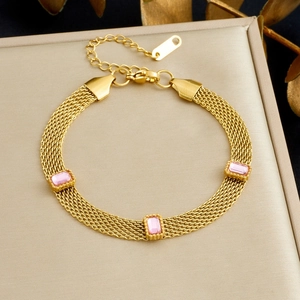 Détail du bracelet chaîne en maille dorée avec trois pierres roses sur boîte à bijoux