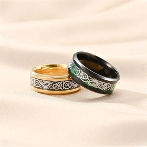 Close-up of gold and black stainless steel rings with Celtic dragon pattern on silk