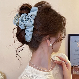 Detail of light blue polka dot fabric heart hair claw clip on a bun hairstyle