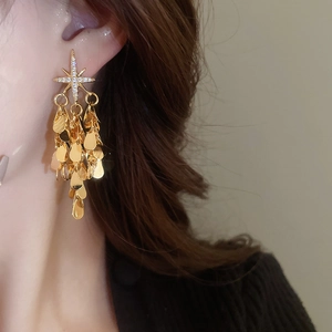 Boucles d'oreilles étoile avec pompon goutte dorée portées par un mannequin