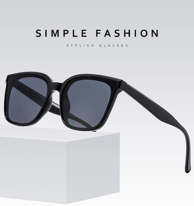 Detail view of stylish large black frame sunglasses with dark grey lenses on white cube
