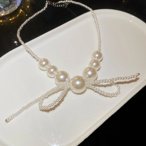Elegant gold-plated pearl necklace featuring a bow design with gradient white pearls