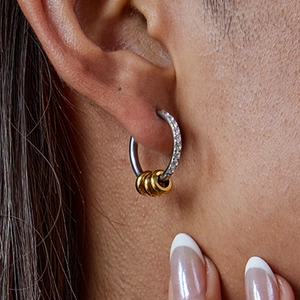 Close-up of minimalist gold and silver tiered hoop earrings with white diamonds on model