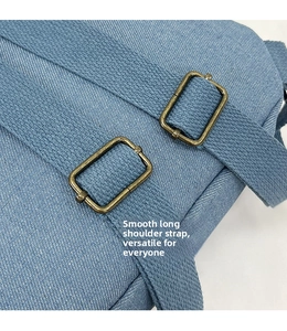 Detail of adjustable blue canvas straps with vintage gold metal buckles on a travel backpack