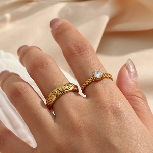 Detail of 18K gold plated ring set featuring sun moon star relief and single crystal stone