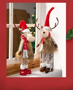 Plush Christmas reindeer dolls with red hats and striped legs on a festive windowsill