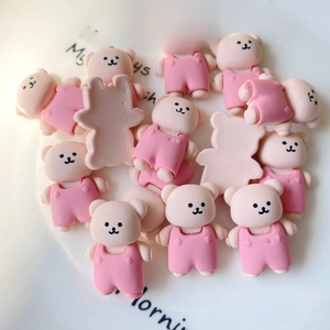 Detail of cute resin pink bears in overalls scattered on a white porcelain decorative tray