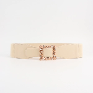 Close-up of beige elastic belt featuring a gold square buckle with rhinestone leaf patterns