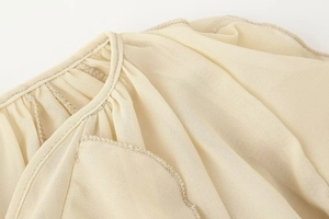 Detailed macro view of beige ruffled V-neckline with delicate pleated chiffon fabric