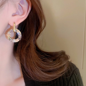Close-up of geometric gold hoop earrings with sparkling crystals worn by a model