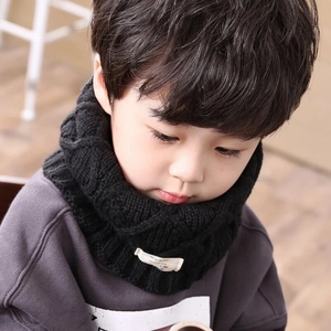 Close-up of black knitted kids scarf with decorative label and premium stitch detail