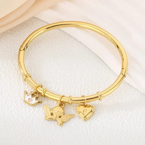 Detail of golden bamboo style bangle with crown, angel, and pink heart charms