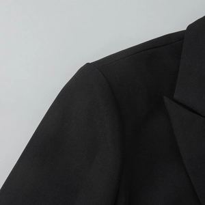 Detailed view of structured shoulder padding and notch lapel on black lace blazer