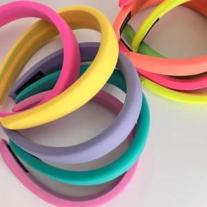 Macro shot of colorful padded velvet headbands with handmade label on white background