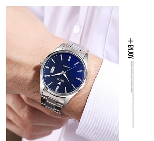 Close-up of a silver men's watch with blue dial and date display on a wrist