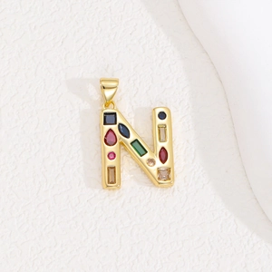 Detailed close-up of a golden letter N pendant featuring vibrant multi-color gemstones