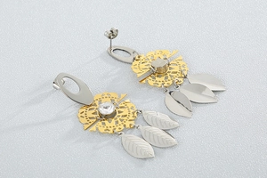 Detail of bohemian long tassel earrings with golden openwork discs and silver metal leaves