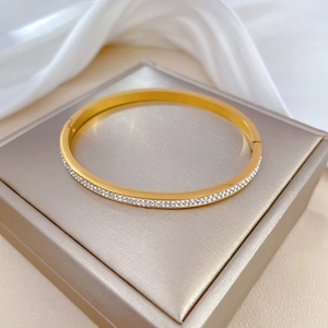 Detailed close-up of a gold titanium steel bracelet with pavé rhinestones on silk