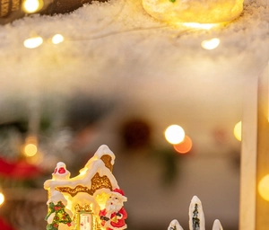 Detail of miniature resin gingerbread house with LED warm light and painted Santa Claus
