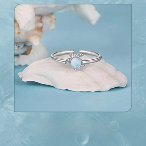 Detail of s925 silver turtle ring with blue gemstone on white seashell background