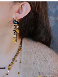 Close-up of ethnic style wooden bead tassel earrings with black rectangle gemstones