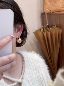 Détail de boucles d'oreilles créoles plaquées or 16k avec perles blanches portées