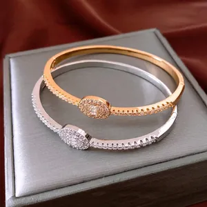 Elegant 18K gold plated oval buckle bangles set with cubic zirconia stones on silk