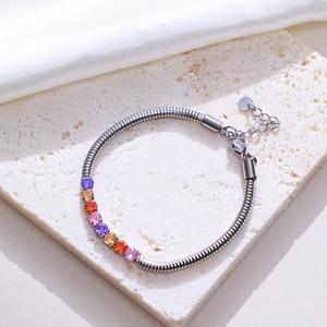 Macro detail of silver snake chain bracelet with colorful round zircon stones on stone base
