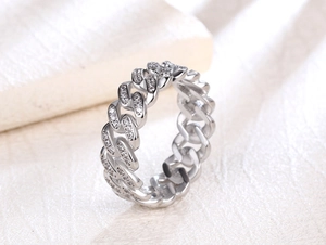 Macro shot of silver-toned Cuban link ring with pavé-set zircons on beige leather