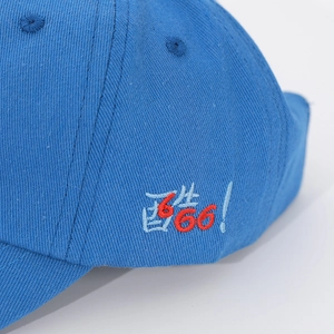 Detail of blue cotton baseball cap with red and blue embroidered text and vent holes