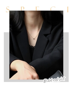 Minimalist gold chain necklace with round zircon pendant worn by model on black suit
