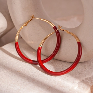 Detail of red enamel and gold hoops on a textured stone surface in professional lighting