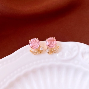 Gros plan de boucles d'oreilles fleur en zircon rose plaquées or avec détails de feuilles