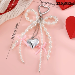 Detail of pearl bow heart keychain with silver LOVE pendant and pink ribbon accents