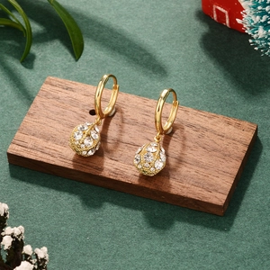 Elegant gold bow earrings with pavé zircons and pearls displayed on a wooden tray