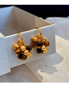 Detail of vintage gold earrings featuring tiger eye stones and textured metal beads
