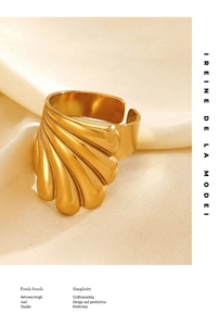 Vue macro d'une bague géométrique dorée en forme de coquillage sur soie beige