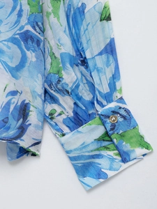 Detail of blue and green floral print sleeve with elegant pleated cuff and gold button