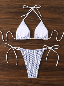 Detailed view of white bikini top with lace mesh bottom and golden metal ring accents