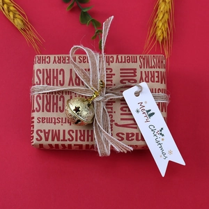 Dettaglio di una scatola regalo di Natale con carta kraft campanella dorata e etichetta