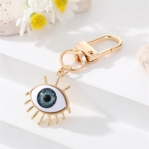 Macro view of evil eye keychain with blue resin eyeball and golden eyelash detail
