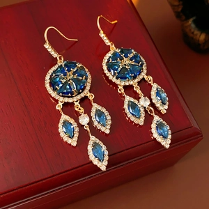 Close-up of vintage gold tassel earrings with blue stones on a red jewelry box