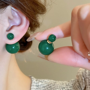 Detailed view of green glass gourd earrings with elegant gold accents on ear