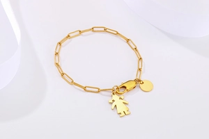 Détail du bracelet chaîne trombone doré avec silhouette de fille et pendentif disque rond