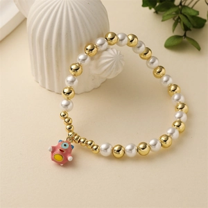 Détail du bracelet avec perles d'imitation, billes dorées et un petit pendentif monstre