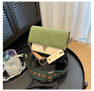 Close-up of tricolor crossbody bag with chain and woven strap on black pedestal