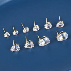 Five pairs of gold drop zircon earrings in graduated sizes on a navy textured background