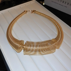 Detail of chunky gold spring coil necklace with bold industrial metal choker design