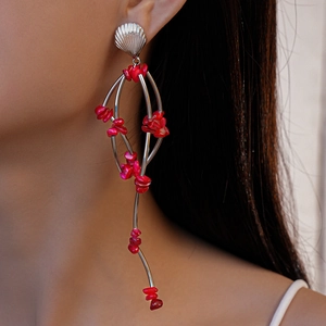 Macro detail of silver shell stud earring with red stone tassels worn by a model
